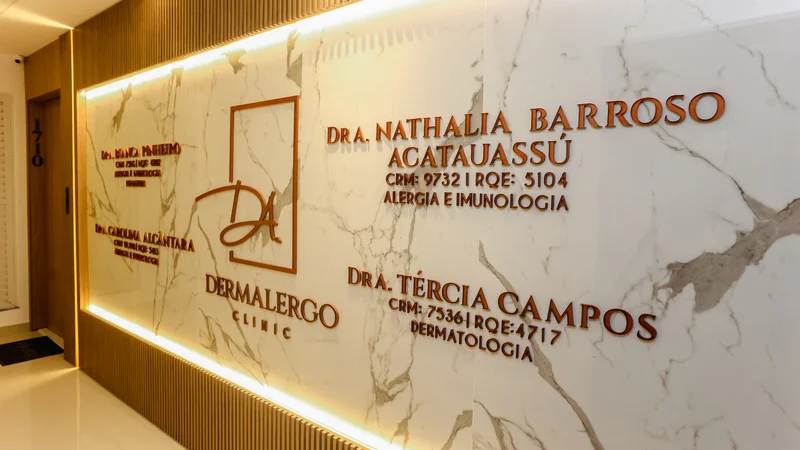 Entrada da clínica com painel de mármore e signage